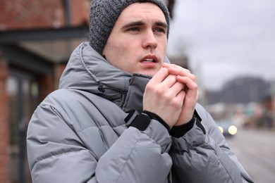 Photo of Sick young man coughing on city street. Cold symptoms