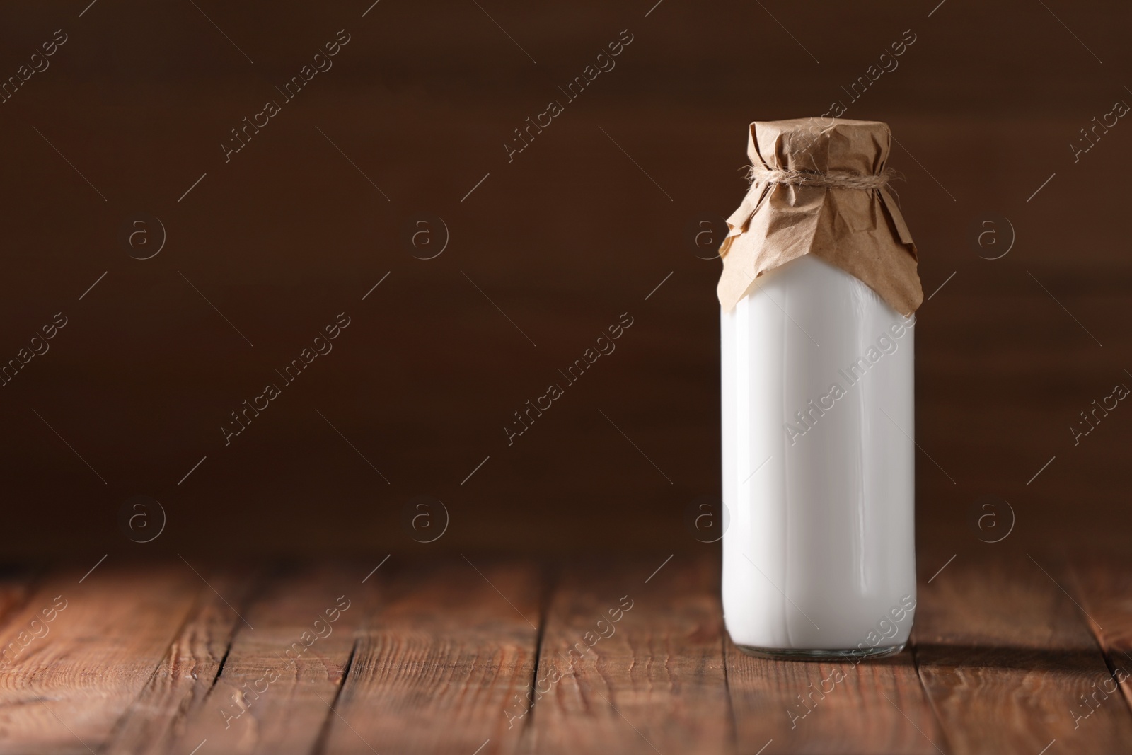 Photo of Tasty fresh milk in bottle on wooden table, space for text