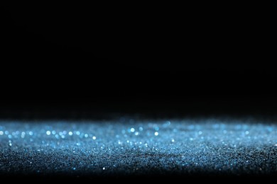 Shiny blue glitter on black background, space for text. Bokeh effect