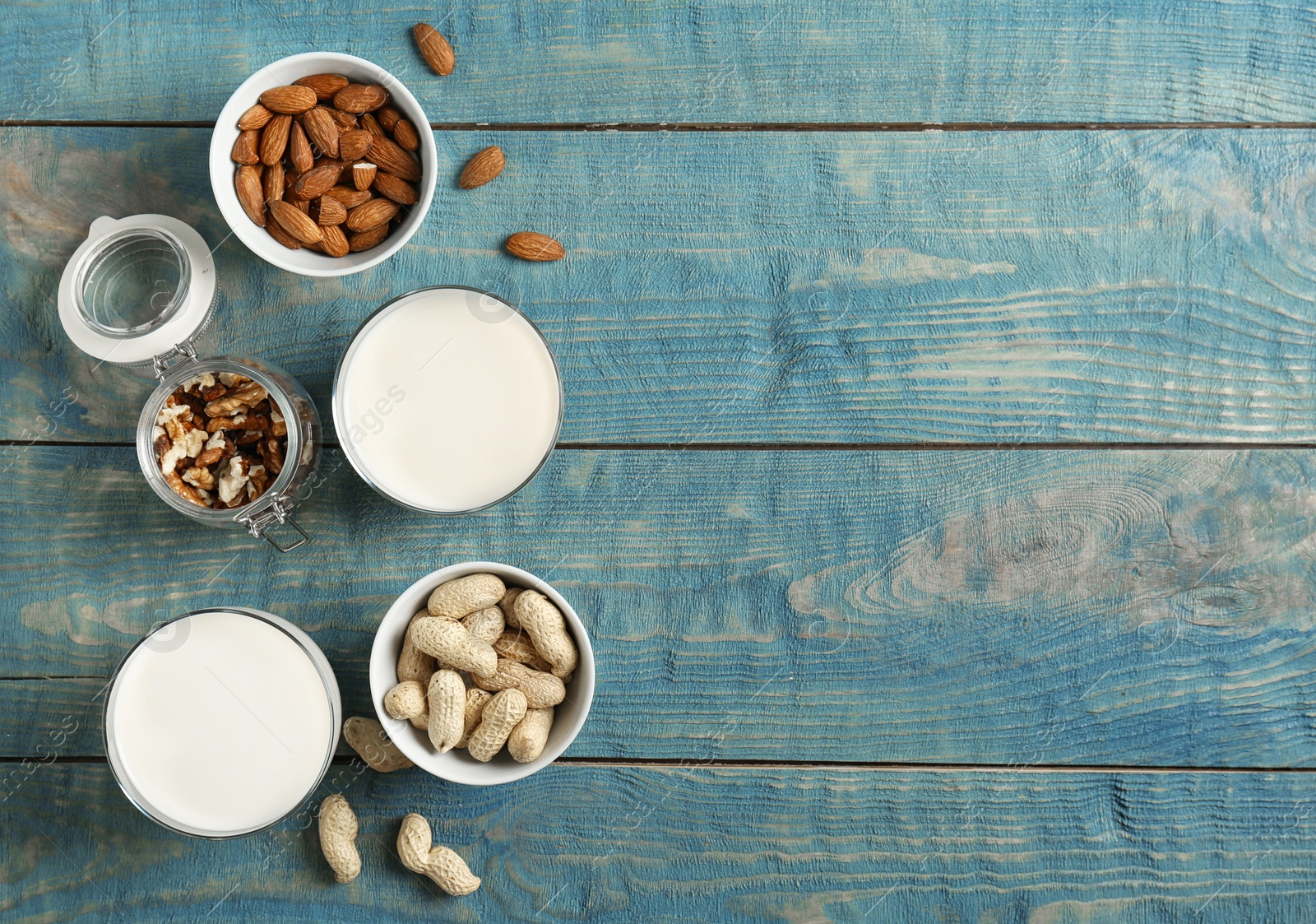 Photo of Glasses with different types of milk and nuts on wooden background