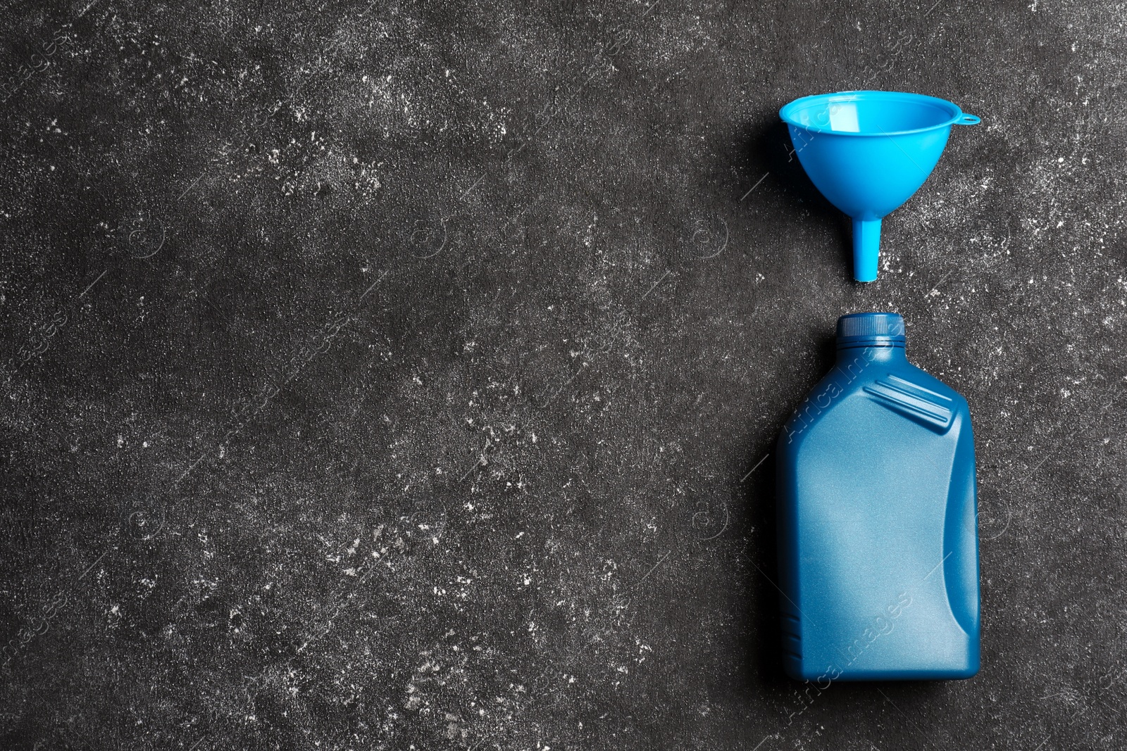 Photo of Light blue canister with motor oil and plastic funnel on grey table, top view. Space for text