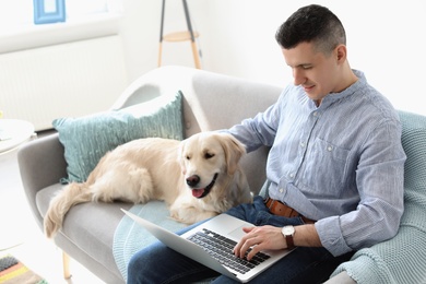 Photo of Portrait of owner with his friendly dog using laptop at home