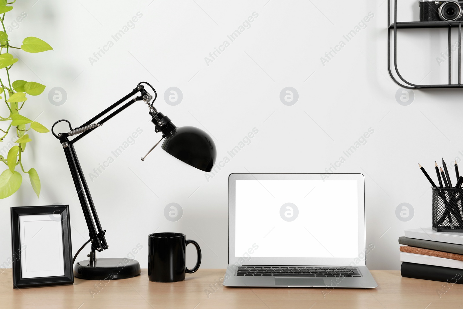 Photo of Cozy workspace with laptop, lamp and stationery on wooden desk at home