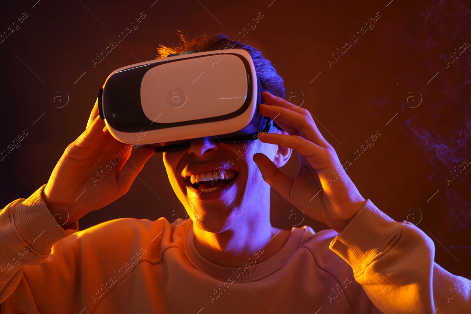 Photo of Young man with virtual reality headset on brown background