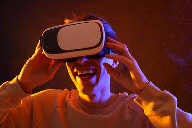 Photo of Young man with virtual reality headset on brown background