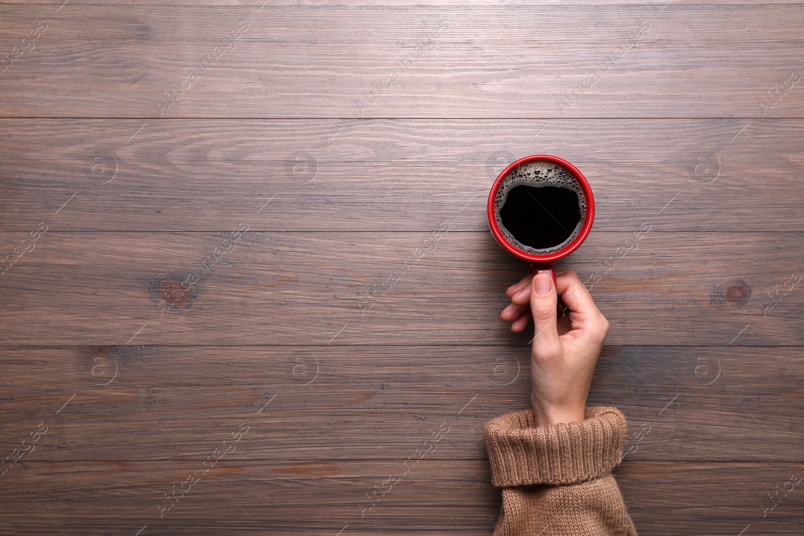 Photo of Woman with cup of coffee at wooden table, top view. Space for text