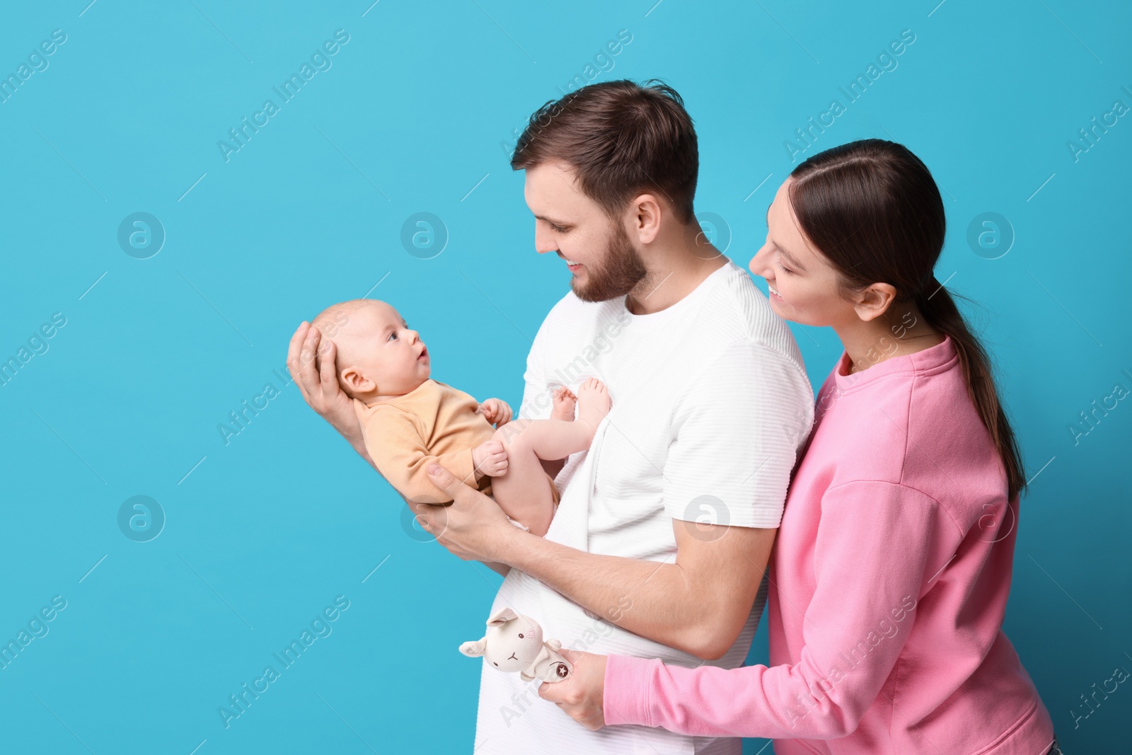 Photo of Happy family. Parents with their cute baby on light blue background