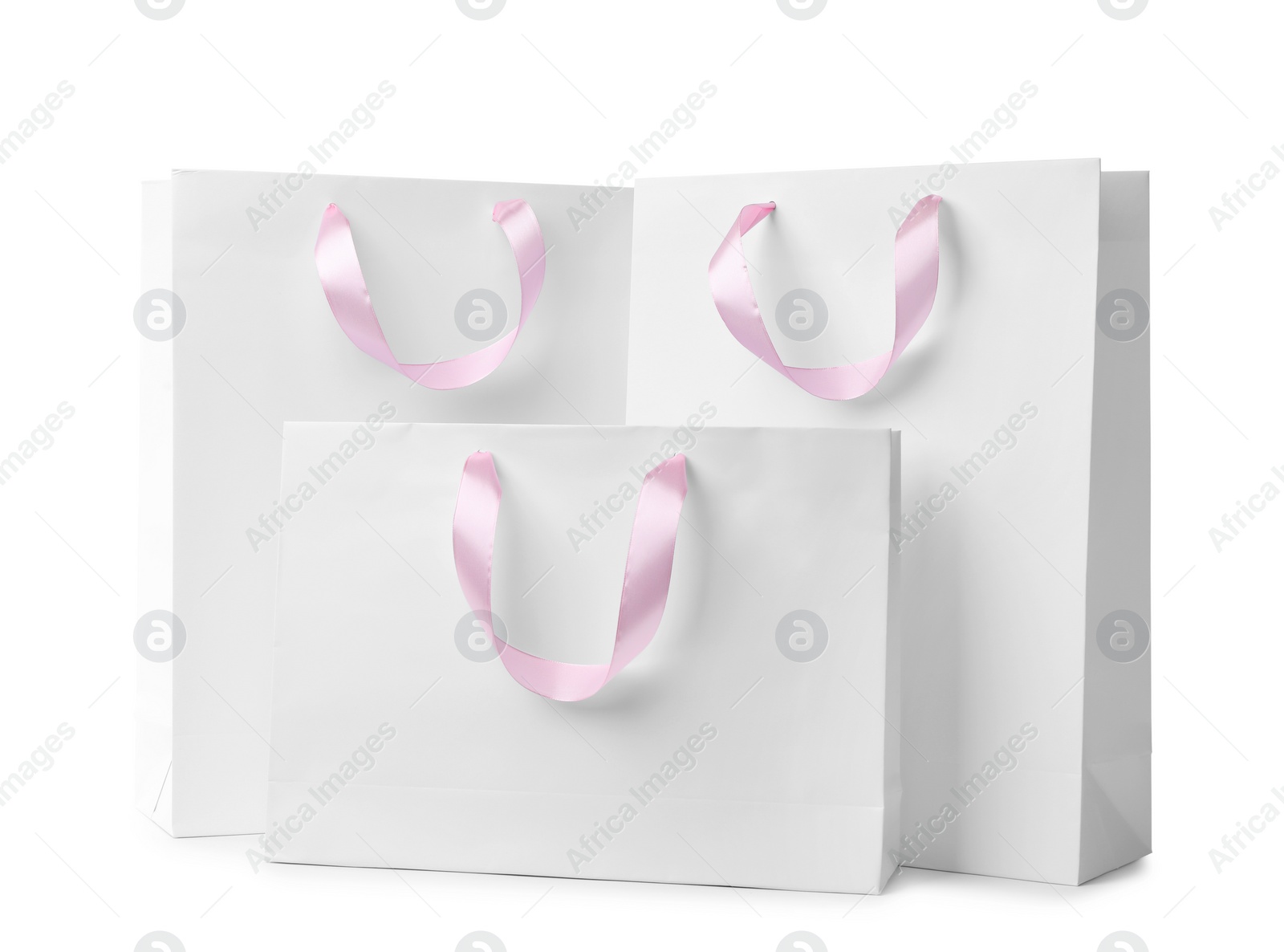 Photo of Paper shopping bags with ribbon handles on white background. Mockup for design