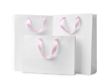 Paper shopping bags with ribbon handles on white background. Mockup for design