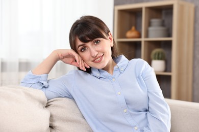 Photo of Portrait of beautiful young housewife on sofa at home