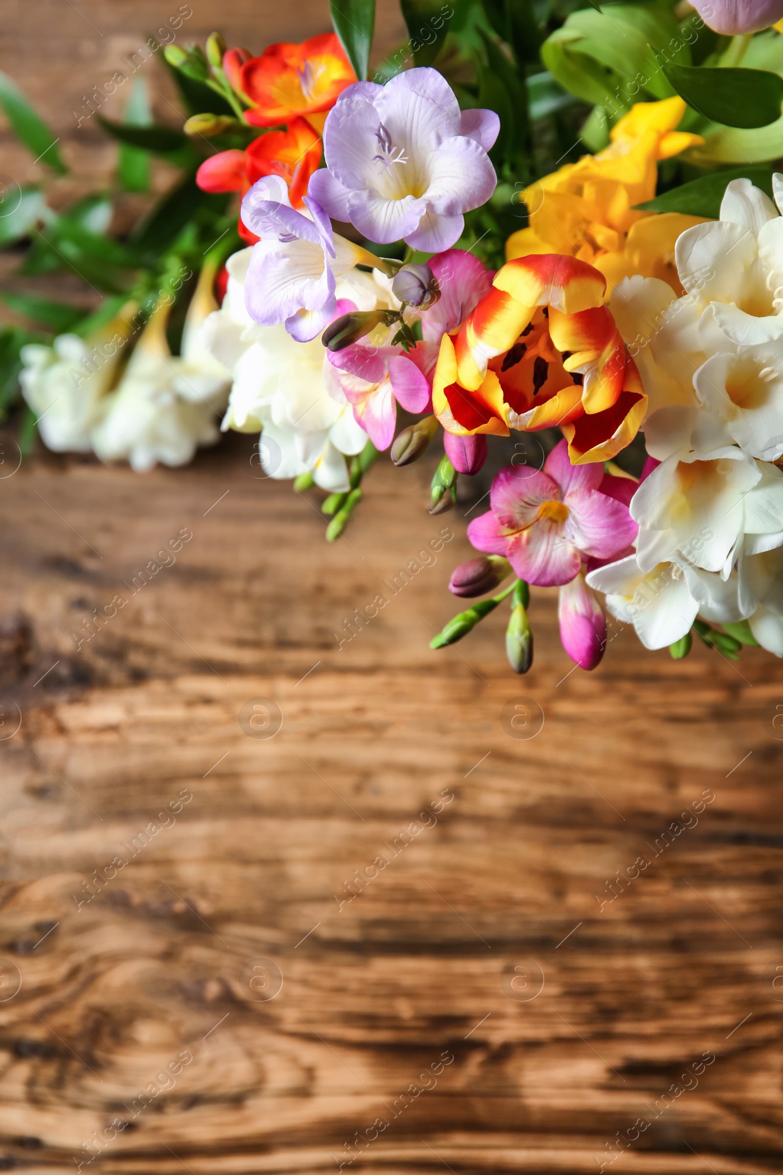 Photo of Beautiful bouquet of freesia flowers on wooden table