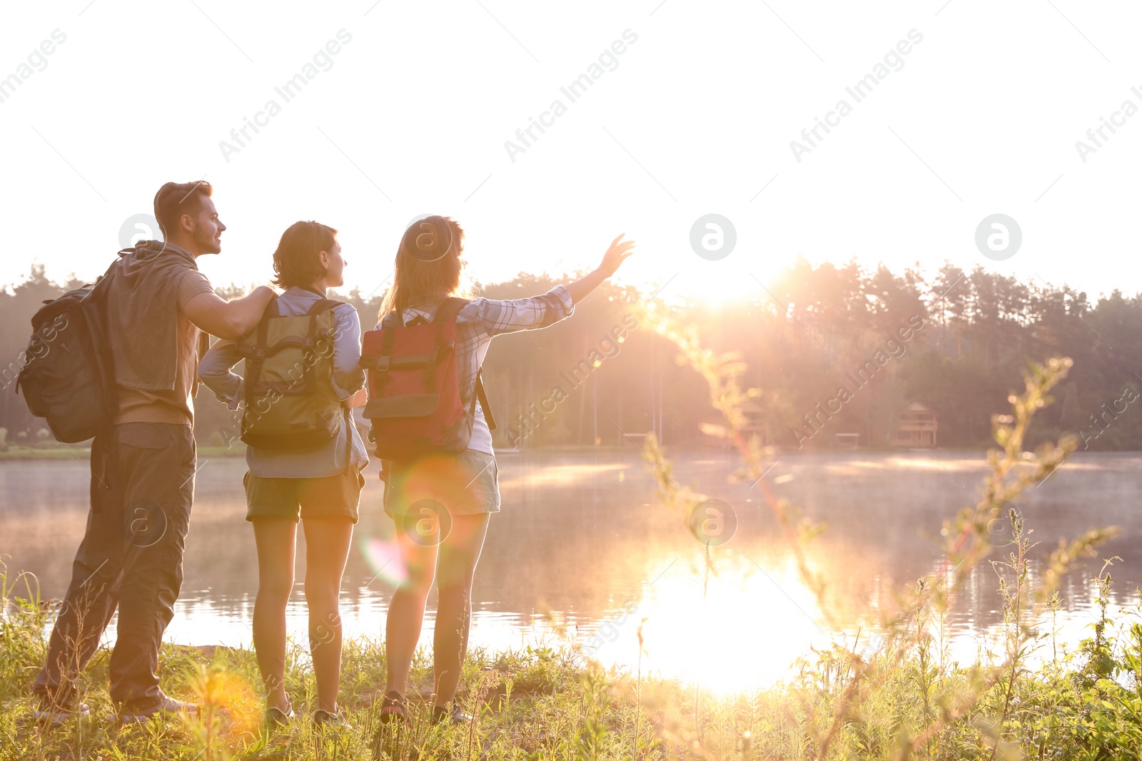 Photo of Young friends on shore of beautiful lake. Camping season