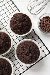 Tasty chocolate muffins on white wooden table, flat lay