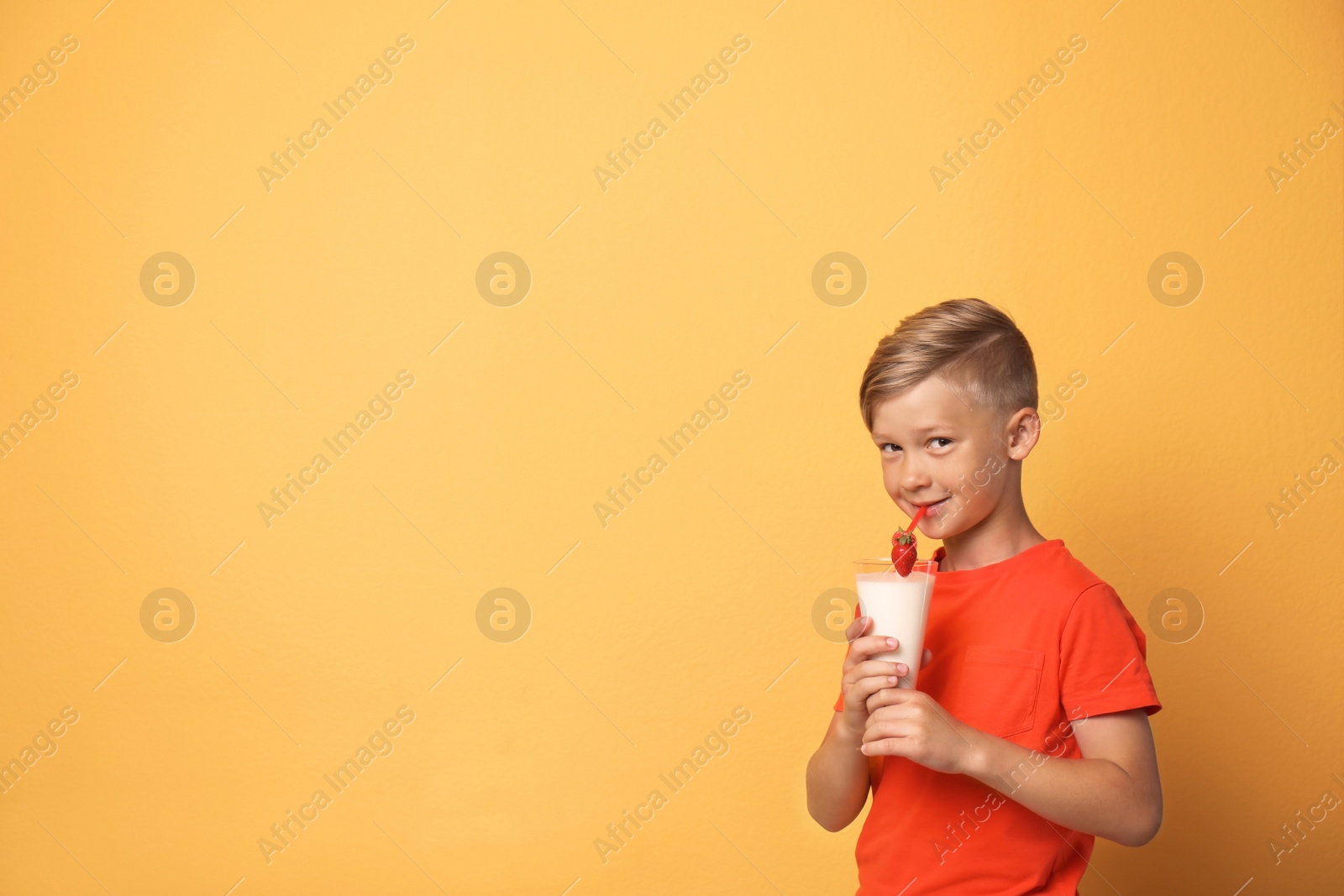 Photo of Little boy with glass of milk shake on color background