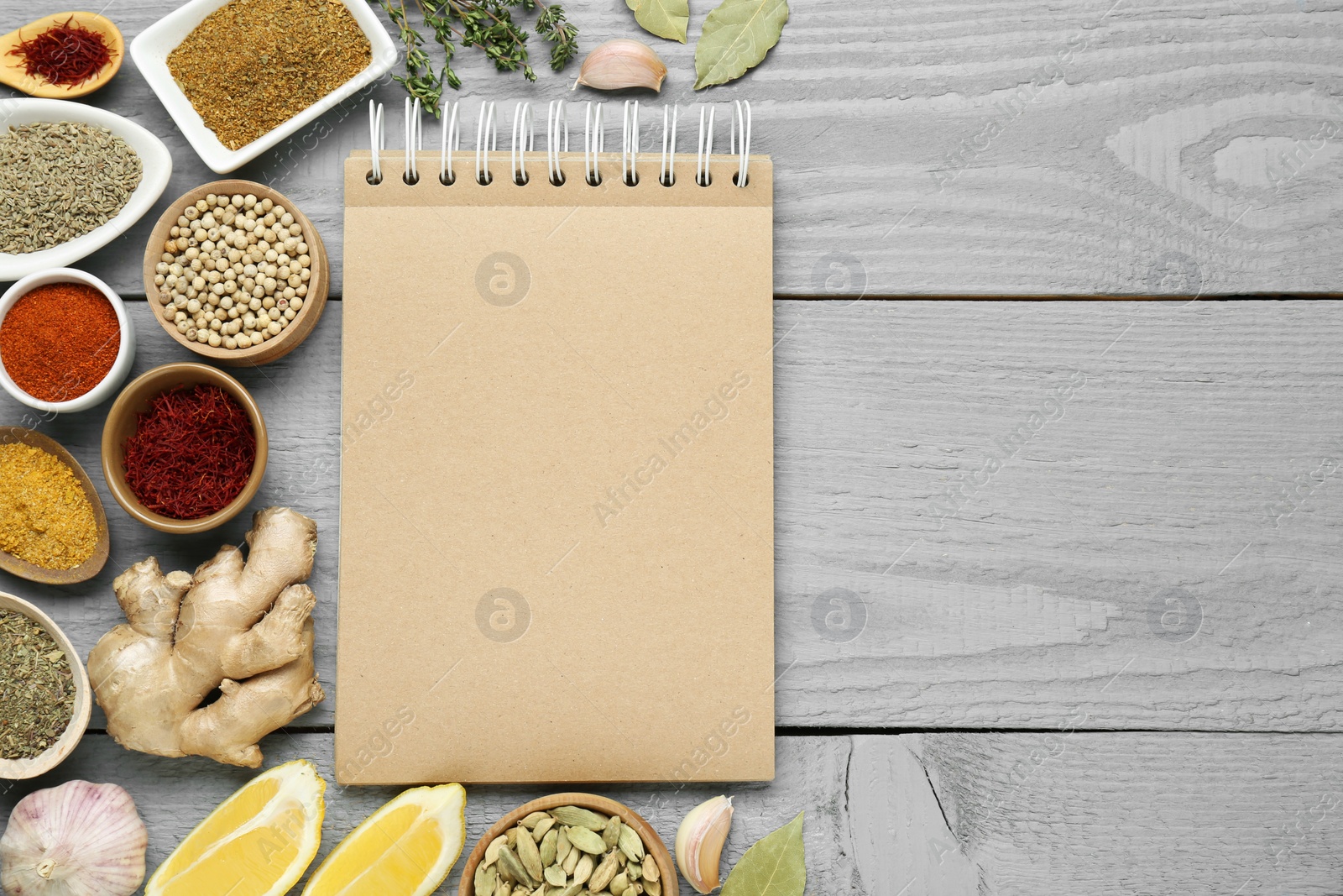 Photo of Blank recipe book and different ingredients on grey wooden table, flat lay. Space for text