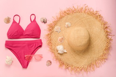 Stylish bikini and beach accessories on pink background, flat lay