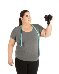 Photo of Overweight woman with grapes and measuring tape on white background