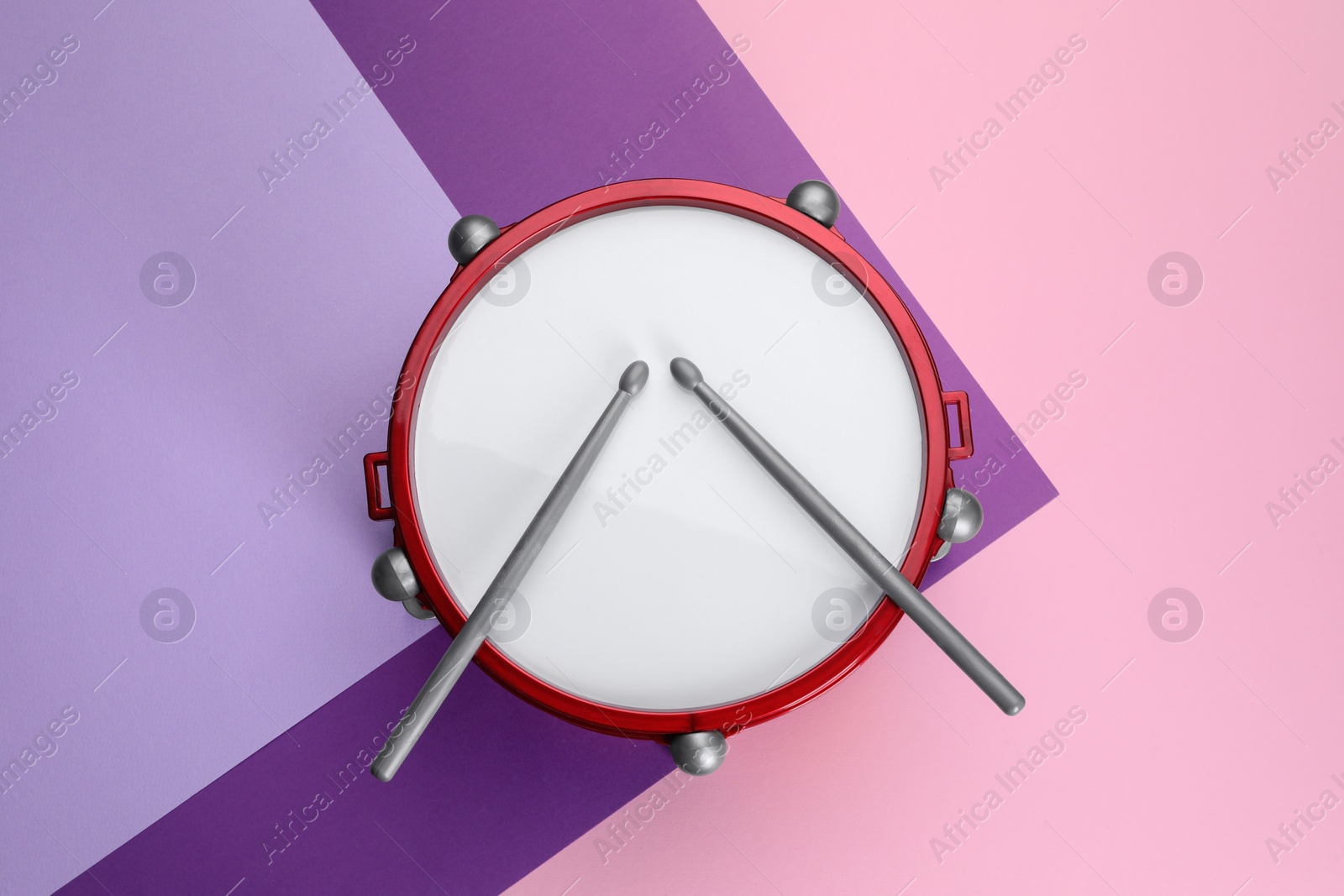 Photo of Children's drum with drumsticks on color background, top view