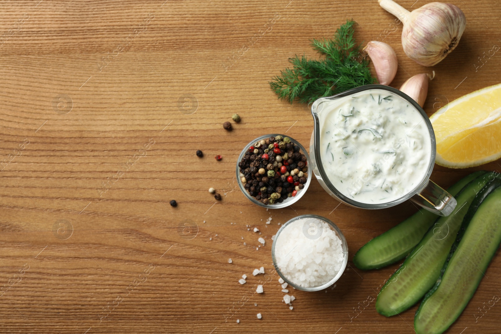 Photo of Cucumber sauce, ingredients and space for text on wooden background, flat lay. Traditional Tzatziki