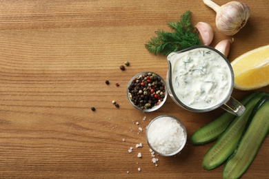 Photo of Cucumber sauce, ingredients and space for text on wooden background, flat lay. Traditional Tzatziki