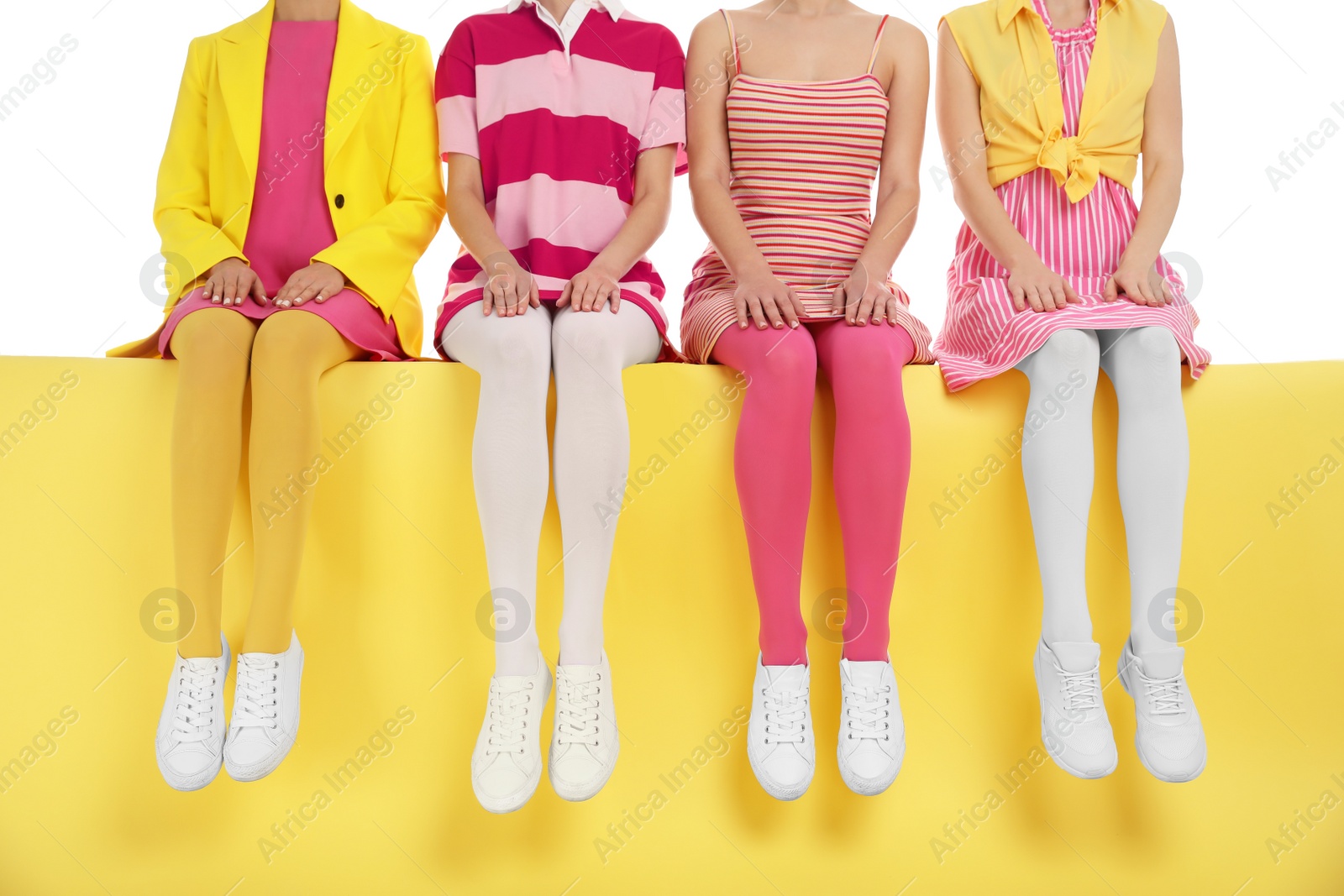 Photo of Women wearing bright tights sitting on color background, closeup
