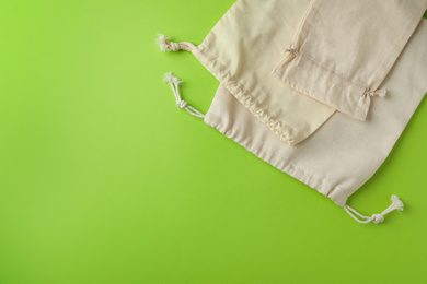 Photo of Cotton eco bags on light green background, flat lay. Space for text