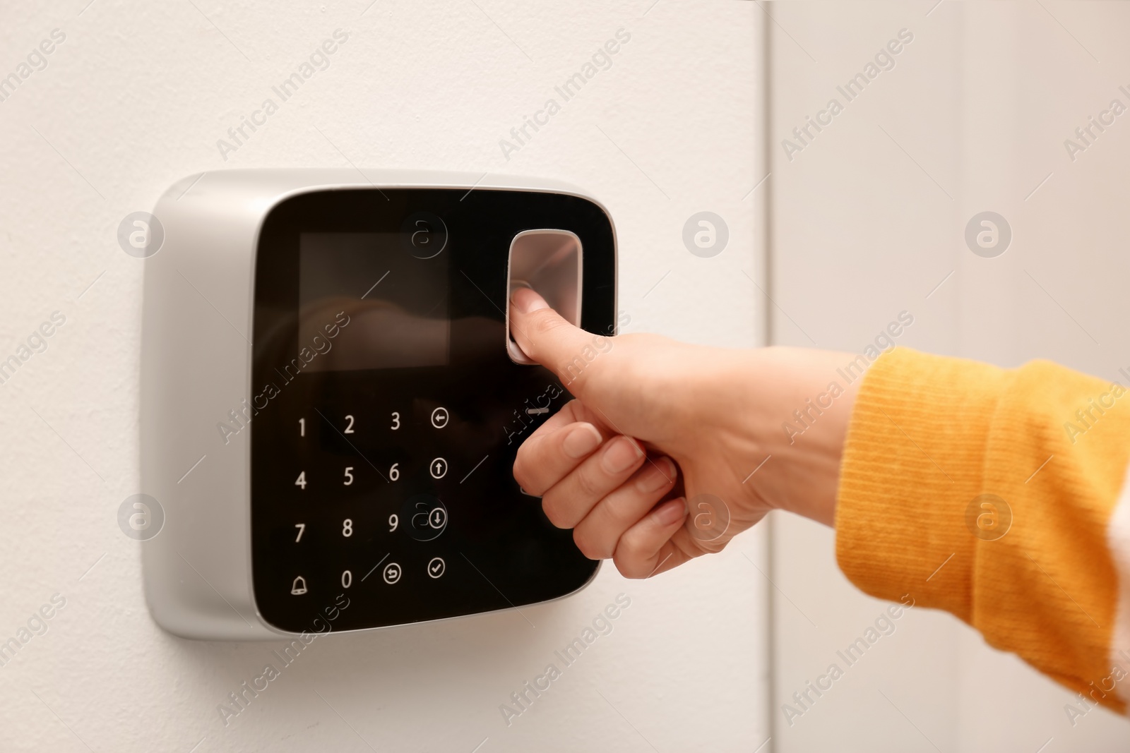 Photo of Woman scanning fingerprint on alarm system indoors, closeup