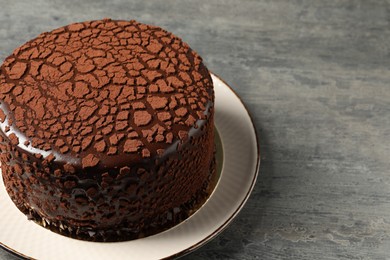 Photo of Delicious chocolate truffle cake on grey textured table, space for text