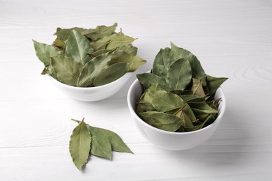 Photo of Bay leaves in bowls on white wooden table