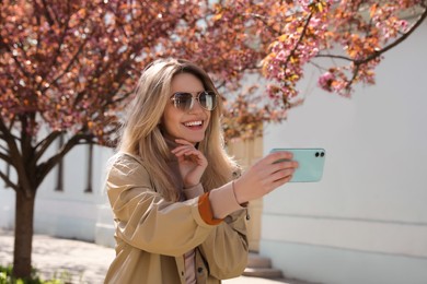 Young woman taking selfie on city street