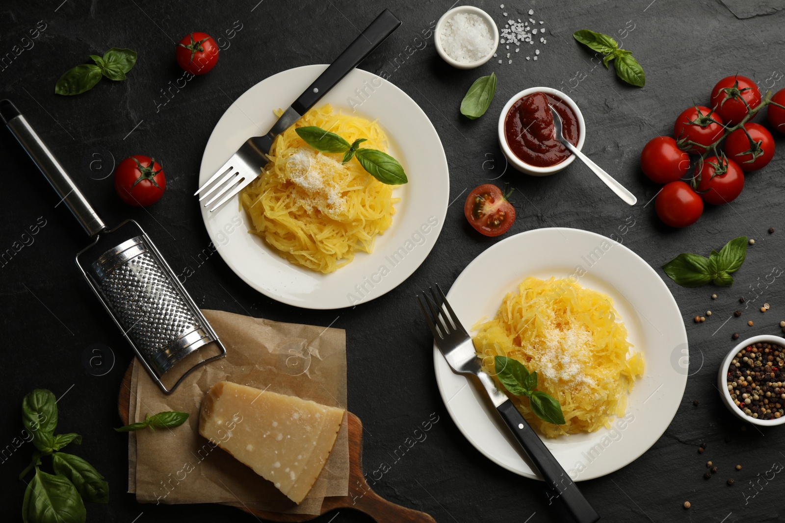 Photo of Tasty spaghetti squash with basil and cheese served on black table, flat lay