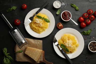 Photo of Tasty spaghetti squash with basil and cheese served on black table, flat lay