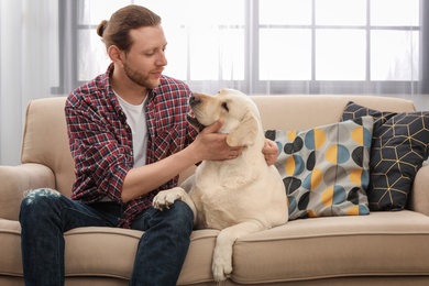 Photo of Adorable yellow labrador retriever with owner on couch indoors