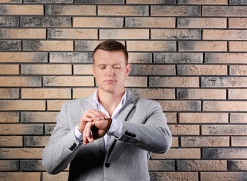 Handsome young man in suit near brick wall background