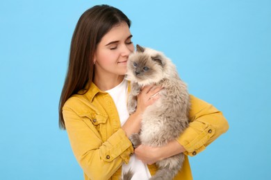 Woman with her cute cat on light blue background