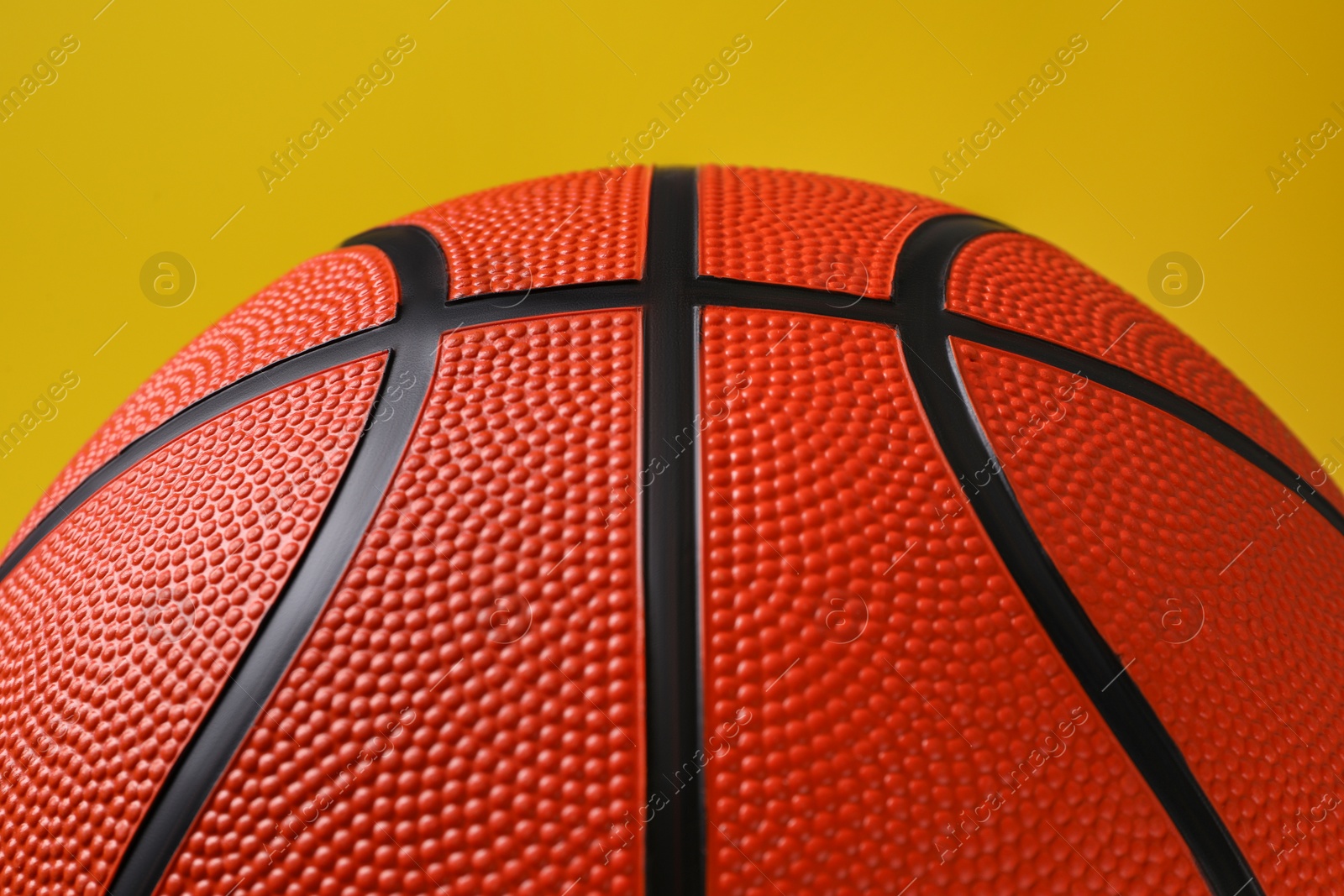 Photo of One new basketball ball on yellow background, closeup