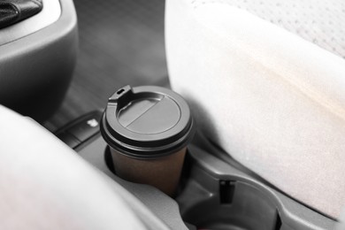 Photo of Coffee to go. Paper cup with tasty drink in holder inside of car, closeup