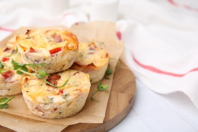 Photo of Delicious egg muffins with cheese on white tiled table, closeup. Space for text
