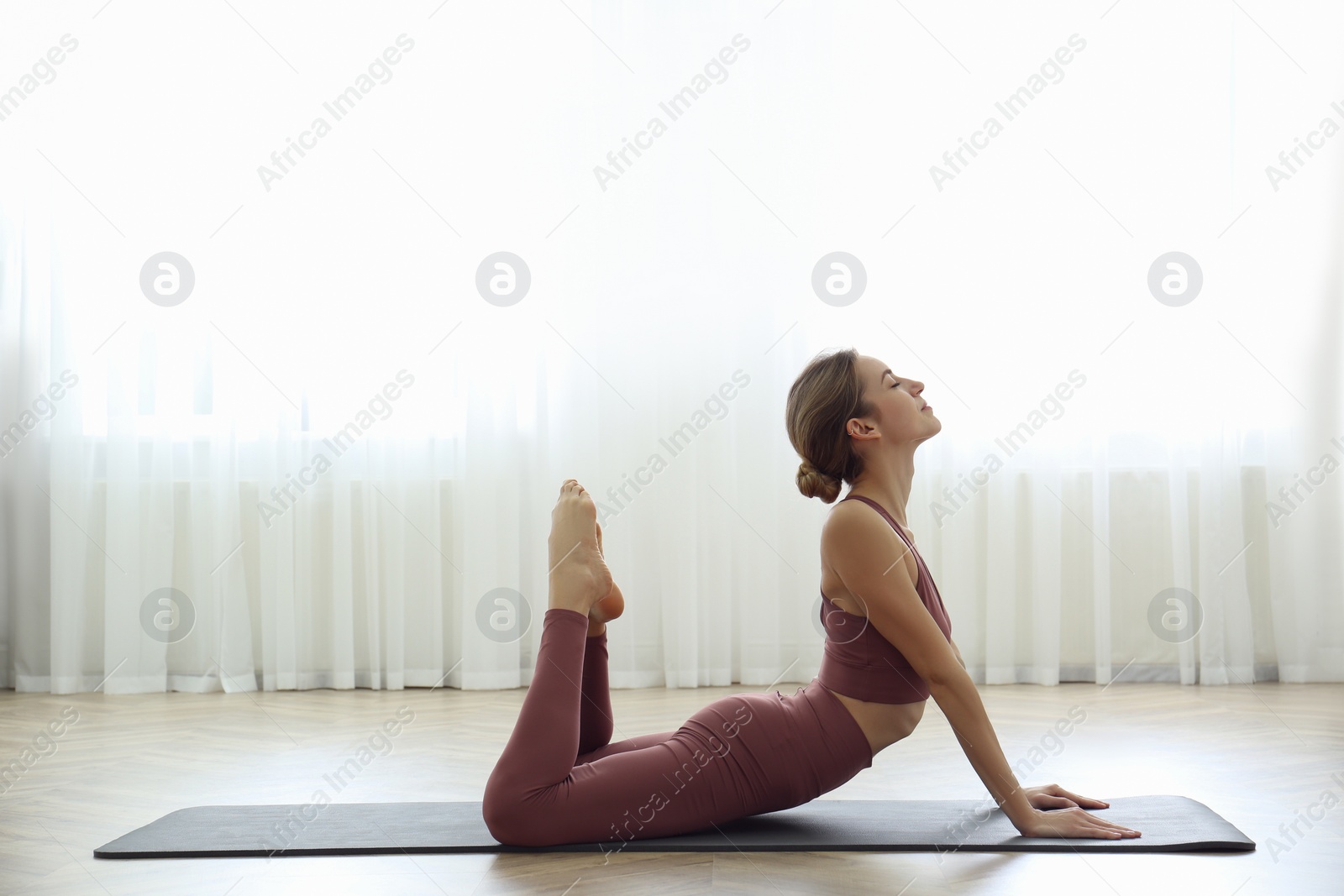 Photo of Young woman practicing king cobra asana in yoga studio. Raja Bhujangasana pose