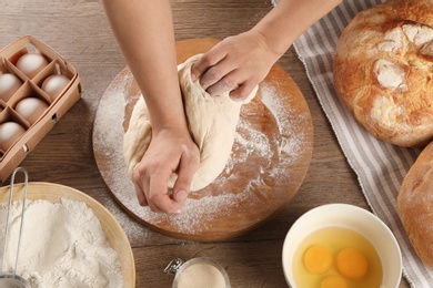 Photo of Female baker preparing bread dough at kitchen table, above view