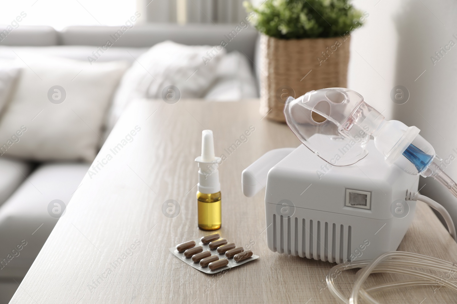 Photo of Modern nebulizer with face mask and medications on wooden table indoors. Inhalation equipment