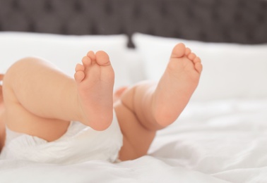 Cute little baby lying on bed, closeup of legs