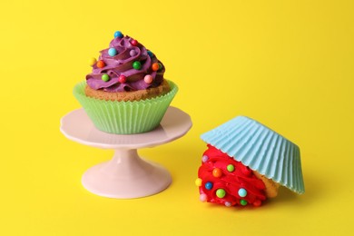Photo of Dropped and good cupcakes on yellow background. Troubles happen