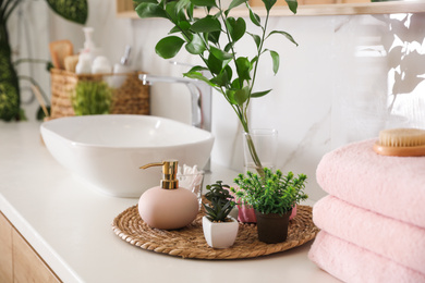 Photo of Green plants and toiletries on white countertop in bathroom. Interior design