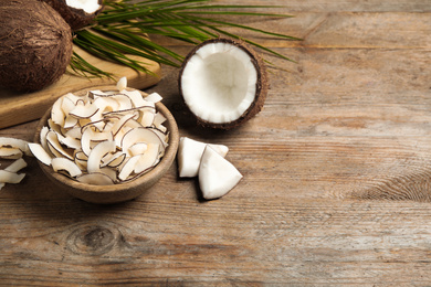 Photo of Composition with tasty coconut chips on wooden table. Space for text