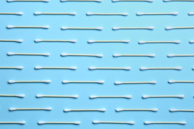 Photo of Many cotton buds on light blue background, flat lay