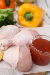 Photo of Fresh marinade and raw chicken drumsticks on board, closeup