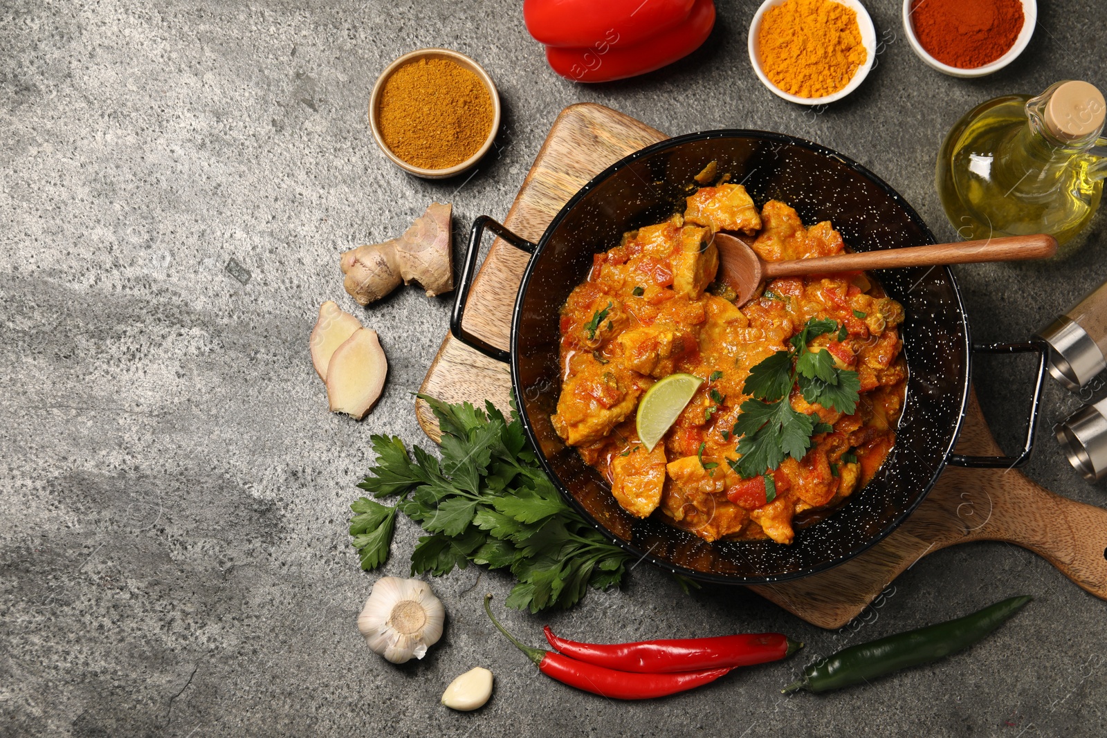 Photo of Delicious chicken curry and ingredients on grey table, flat lay. Space for text