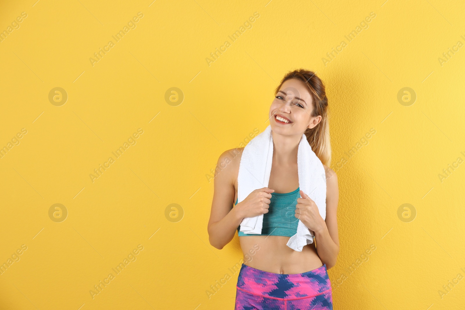 Photo of Beautiful young woman in sportswear with towel on color background. Space for text