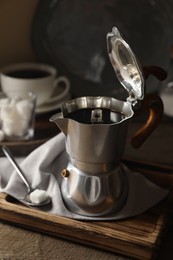 Brewed coffee in moka pot and sugar cube on wooden table